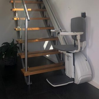 een rechte traplift met grijsstoeltje op een rechte moderne trap